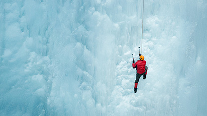 Klatrer som skalerer stor isete klippe